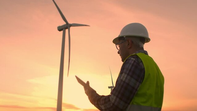 Windmill engineer watching wind turbines in operation on a tablet