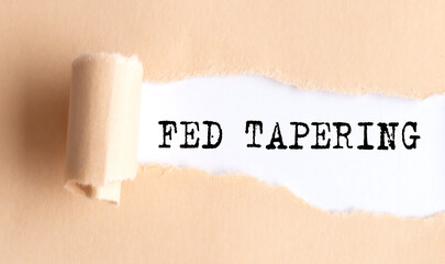 The text FED TAPERING appears on torn paper on white background.