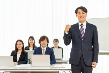 セミナーの男性講師とスーツ姿の男女（ガッツポーズ）
