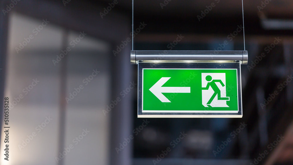 Wall mural illuminated emergency exit sign. arrow pointing to the left.
