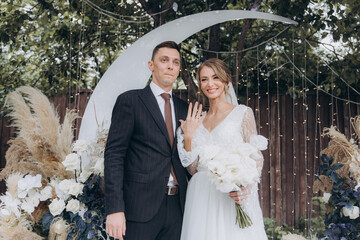 Beautiful space wedding ceremony in the summer of a chic couple, the groom in a suit and the bride in a white luxurious wedding dress.