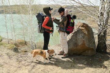 Young Asian woman hiking together with best friend helping her to adjust travel backpack after break