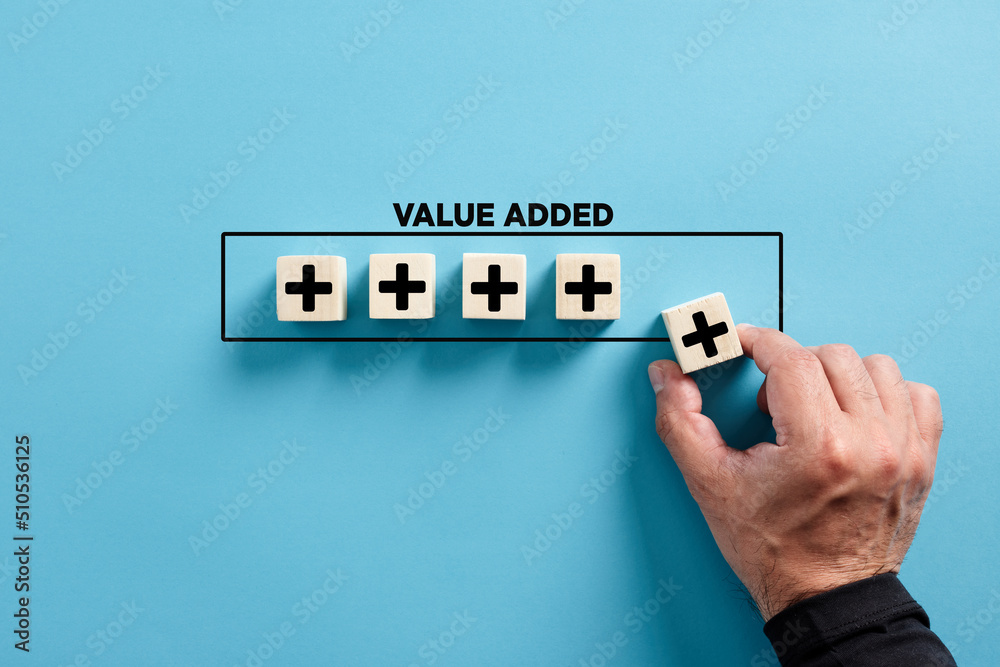 Wall mural male hand puts the wooden cube with plus icon with the word value added. profit, benefit growth and 