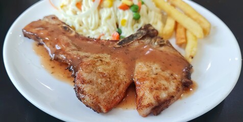 Black Pepper Pork Steak Topped with a delicious black pepper sauce. Served with french fries and vegetable salad.