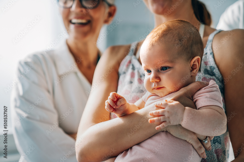 Wall mural Closeup portrait of a happy newborn baby in the arms of mother. Family love parenting concept