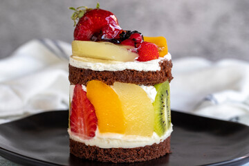 Fruit cake. Cake surrounded by fruits on a stone background. Patisserie products. Close-up.