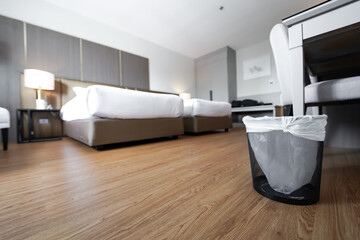 A container trash in the room with plastic inside it in hotel and resort bedroom with wooden floor...