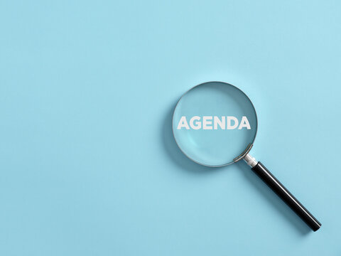 Magnifier focuses on the word agenda. Concept of plans, appointments and to do list in business.