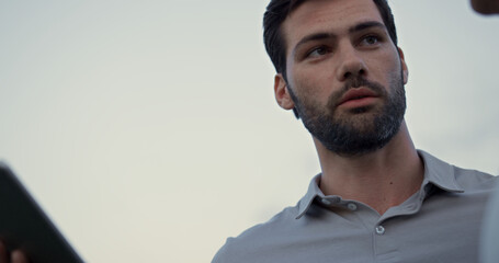 Obraz premium Man face looking tablet screen outdoors. Sexy guy talking online on golf course.