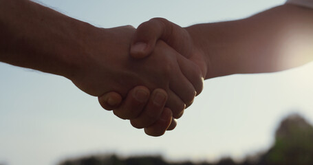 Caucasian people shaking hands outdoors. Two business partners on summer nature.