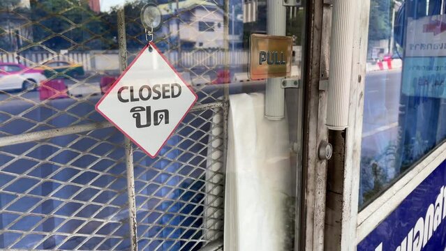 Closed sign on window glass at storefront with traffic on road - day 