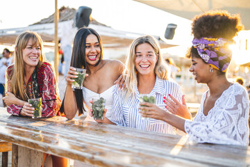 Group of young and attractive women having fun and drink at chiringuito, beautiful girls on vacation sitting at chiringuito table on sunset and having fun at summer party
