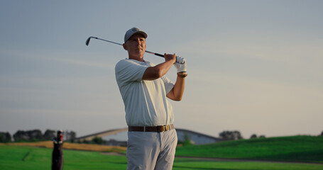 Excited golfer playing golf on field. Rich senior practicing sport activity game