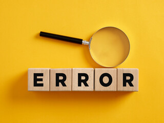 The word error on wooden cubes with a magnifier. To find, reveal or analyze a system error