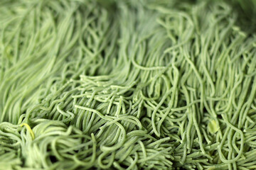 Raw homemade Italian green pasta spaghetti. Selective focus, top view, copy space.