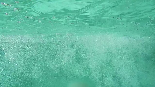 Woman Swimming Backstroke in Swimming Pool Seen from Underwater in Switzerland.