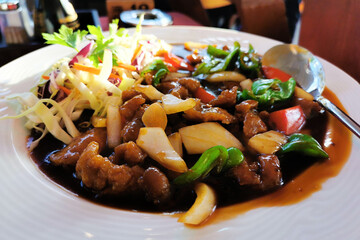 Pork with Chinese hot sauce on a white plate.