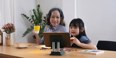 Asian grandmother and granddaughter happily pencil drawing at home