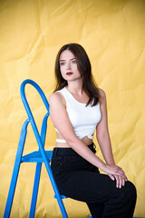 Fototapeta na wymiar Indoor portrait of young girl sitting on a chair on the yellow background. Freedom and patriot of Ukraine. Pray for Ukraine. Stop war. Blue yellow
