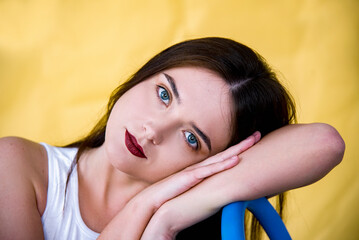 Indoor portrait of young girl sitting on a chair on the yellow background. Freedom and patriot of...