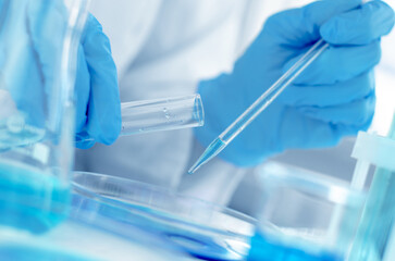 Hands of a scientist with a laboratory pipette. Equipment for chemical experiments. Scientist doing laboratory research