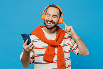 Young smiling cheerful cool happy man 20s in orange striped t-shirt headphones listen to music hold...
