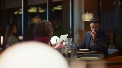 Mixed race couple dating at restaurant table. Lovers choosing menu food in cafe. - obrazy, fototapety, plakaty