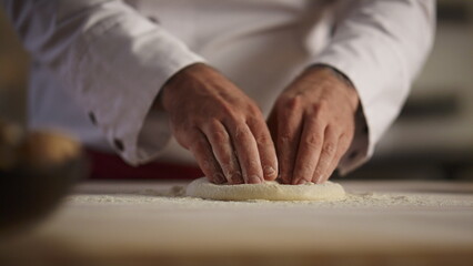 Pastry cook hands knead pizza dough on board. Chef man making bread in kitchen.