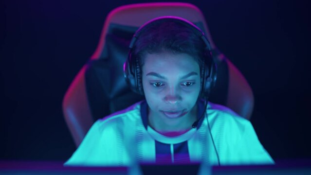 Portrait of a focused female gamer in headphones, plays a video game, cyber sportsman at the championship, blue neon light.