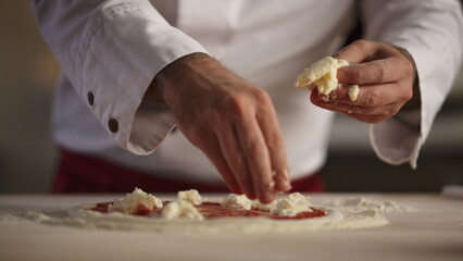 Pizza chef cooking meal in restaurant. Man hands put mozzarella cheese kitchen - obrazy, fototapety, plakaty