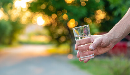 A man holds a glass of water in his hands. Selective focus.