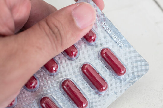 Holding a blister pack of Clindamycin Hydrochloride capsules. 300 mg antibacterial treatment. Medicine for sale at a drugstore or pharmacy.