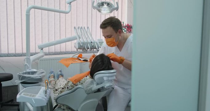 Dentist chair patients dentist examines teeth in clinic man professional doctor wearing gloves and a mask dental equipment makes orthodontic treatment