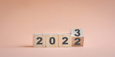 Wooden cube stock flipping, change from 2022 to 2023. Champagne neutral color background, with copy...
