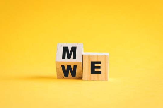 Wooden cube blocks flip from me to we. Teamwork concept. On yellow background.