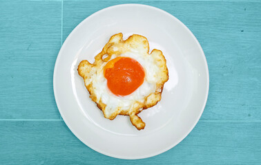 Appetizing fried eggs on a white plate set against a sky blue background.
