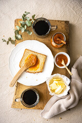 Draufsicht auf ein süsses Frühstück mit Kaffee, Toastbrot und Marillenkonfitüre auf einem Holz...