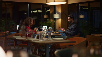 Fototapeta na wymiar Two lovers take photo using mobile phone in restaurant. Couple enjoy dinner date