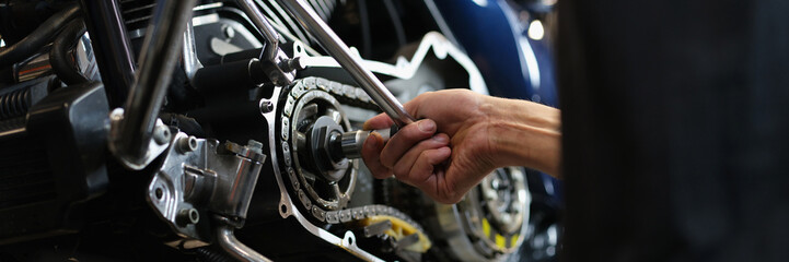 Professional mechanic repair some part of motorbike with equipment