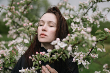 portrait of a beautiful young woman in the spring garden among apple blossom. 
