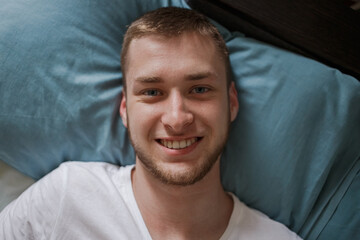 A guy is lying in bed and smiling