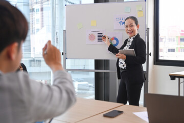 Confident business woman team leader standing near flip chart with graphs diagrams, presenting market research results at meeting