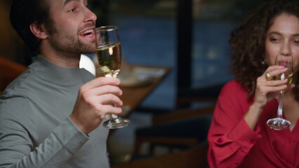 Multiethnic friends make toast in restaurant. Young people clinking drink glass.