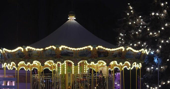 KYIV, UKRAINE JANUARY, 23, 2022 Carousel at night with a lot of lights, winter christmas market, entertainment. People with children sit on horses to ride