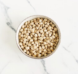 Dried chickpeas in a round bowl top view on a marble background. Superfood.