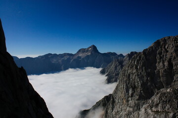 Mountain landscape image of Triglav and its North Face rising from the low fog in the valleys...