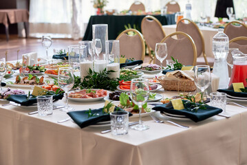 Table setting with sparkling wineglasses, plate with green napkin and cutlery on table, copy space. Place set at wedding reception. Table served for wedding banquet in restaurant