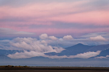 Early sunset colours the sky over low clouds settling in the hills of Nelson