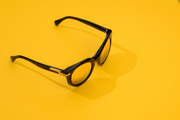 Woman sunglasses in sunlight on pastel yellow background. Modern stylish sunglass for holiday...