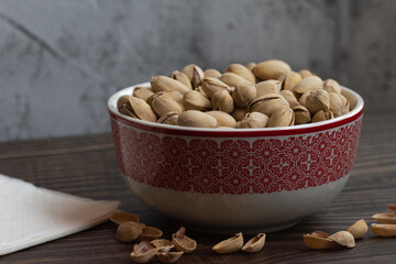 Pistachos con cáscara en un bol sobre una mesa de madera oscura.